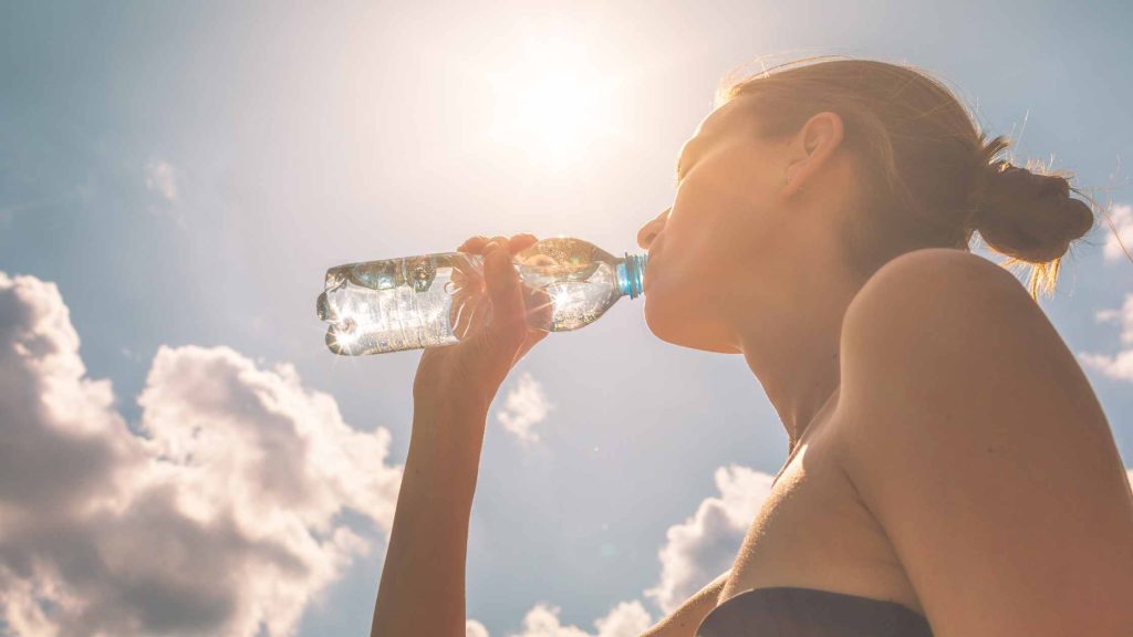 mujer bebiendo agua bajo el sol